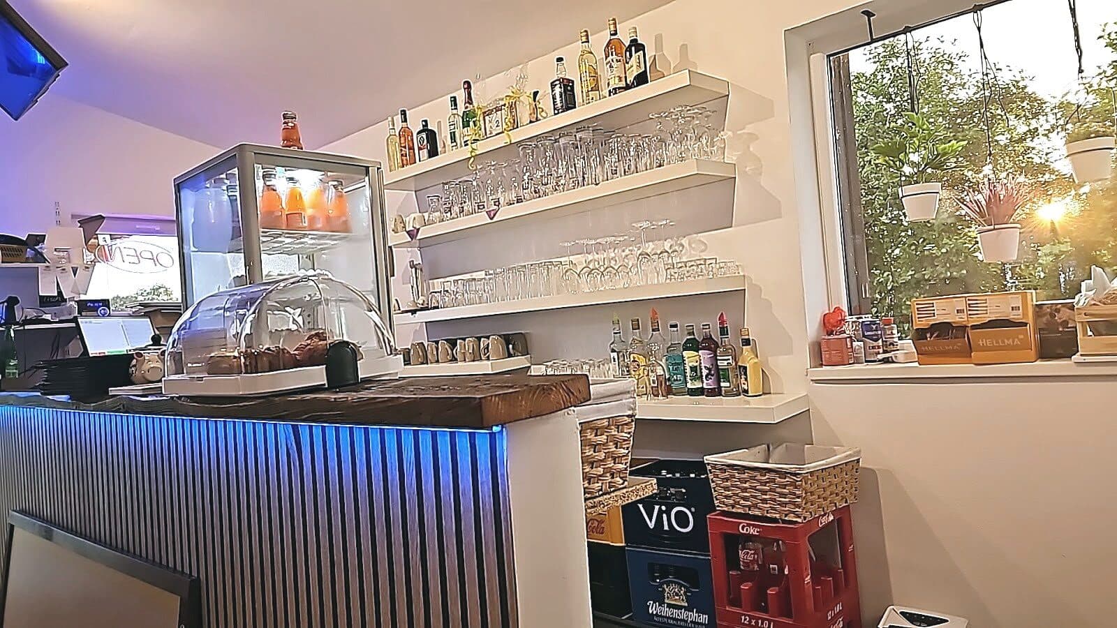 Theke mit Glasvitrine, Gläserregal und Fenster im Abendlicht